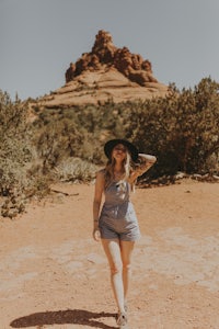 a woman wearing a hat and a denim romper in sedona, arizona