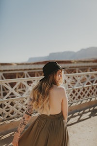 a woman wearing a hat and long dress in the desert