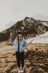 a woman in a blue puffer jacket standing in a snowy field