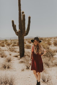 a woman in a red dress standing in front of a cactus