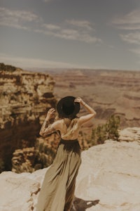 a woman in a long dress standing on a cliff overlooking the grand canyon