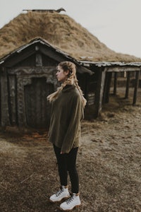 a woman standing in front of a wooden house in iceland