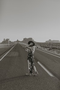 a woman walking down the road in a hat