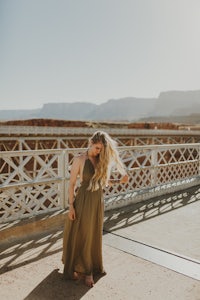 a woman in a long dress standing on a bridge in the desert